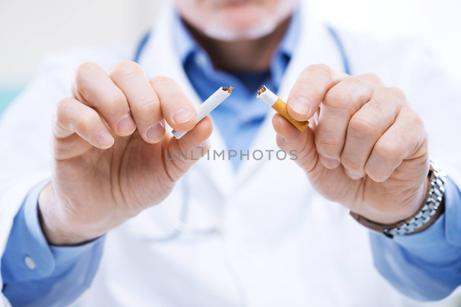 Senior doctor breaking a cigarette, stop smoking concept.