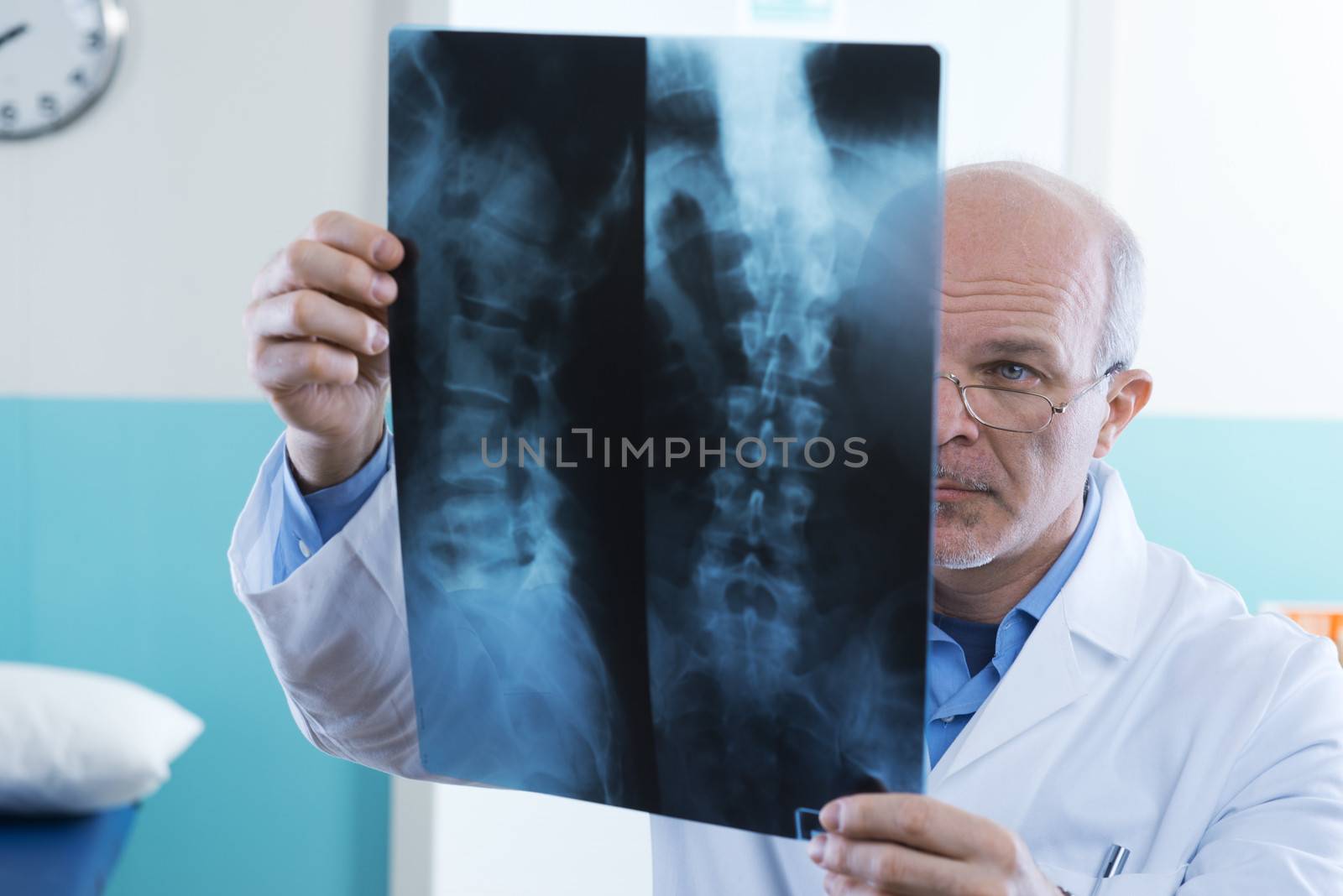 Male senior doctor looking at x-ray images of human spine.