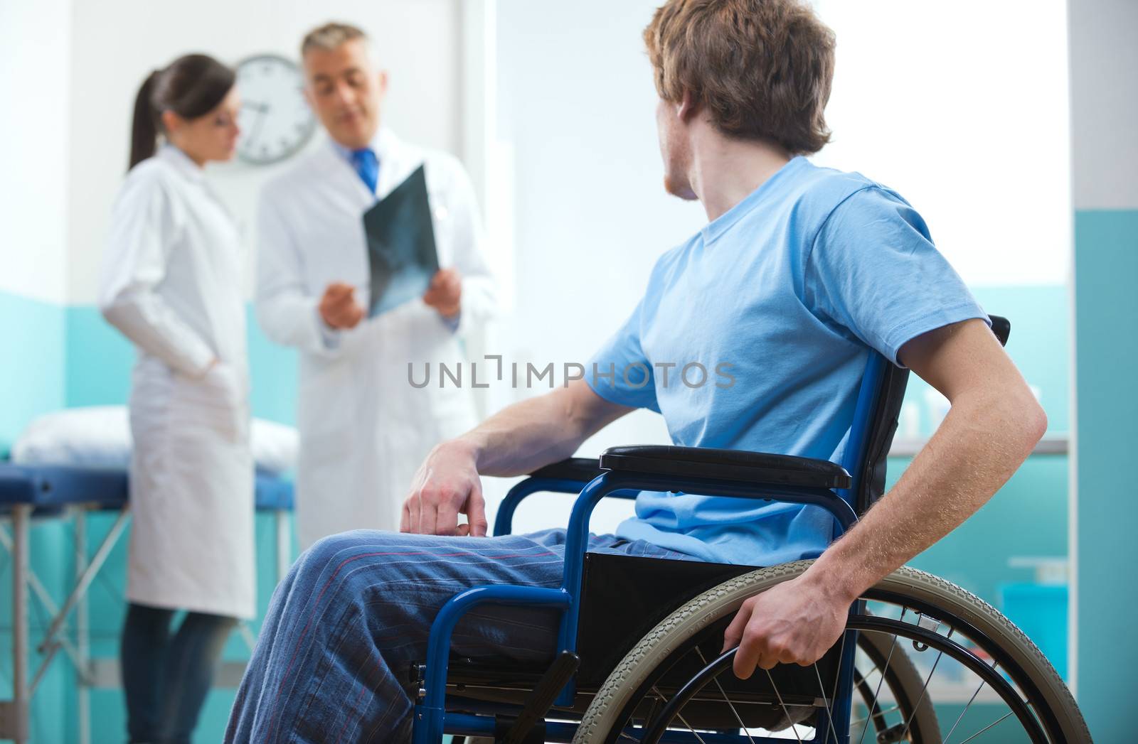 Young patient in wheelchair with doctors in the background.