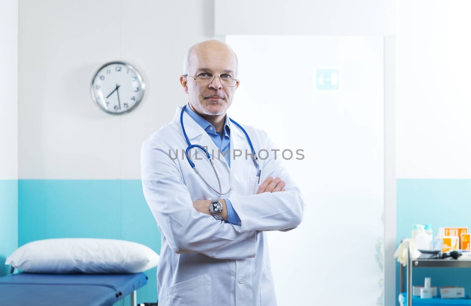 Senior confident doctor in a clinic with arms crossed.