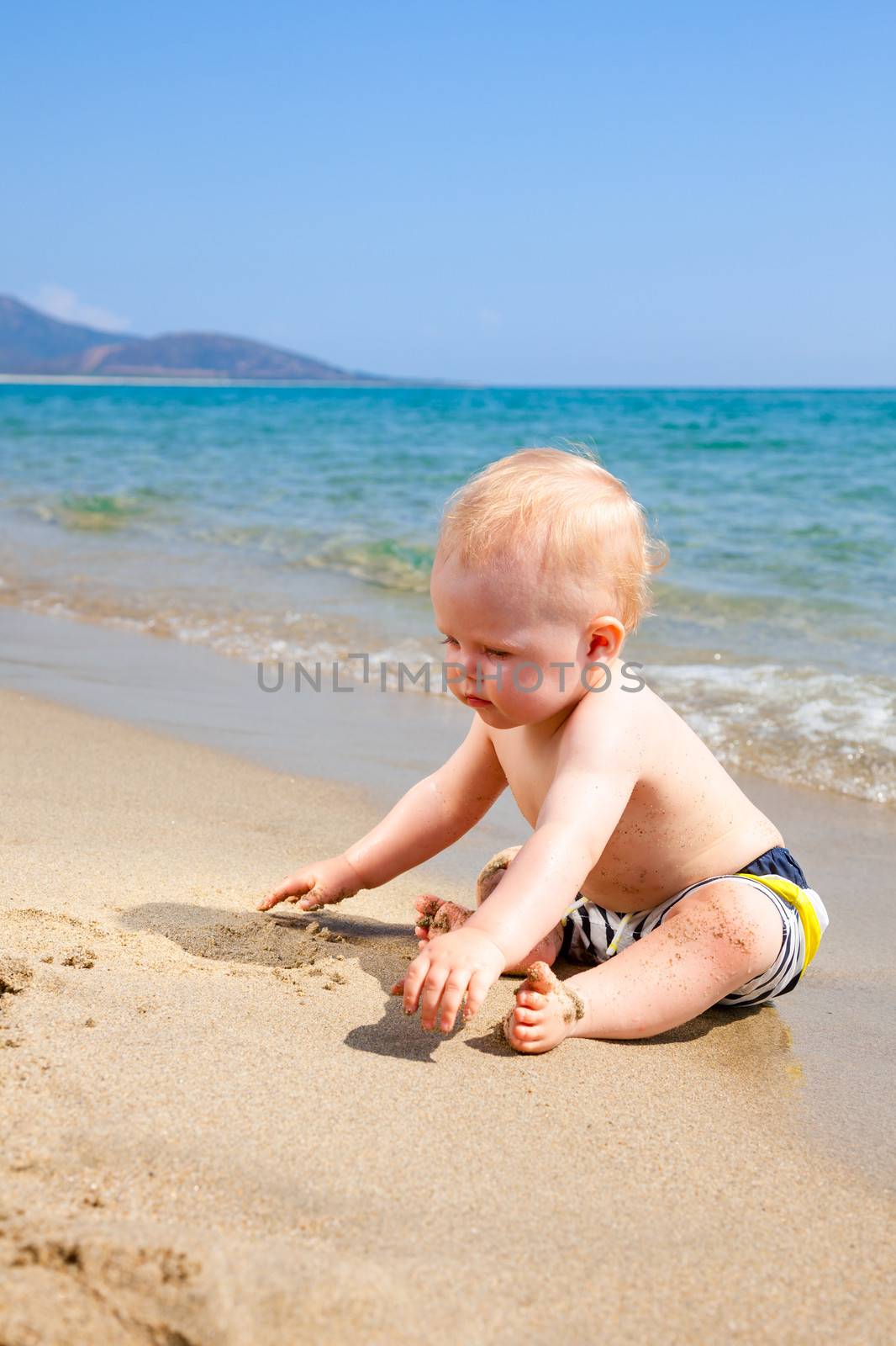 Happy baby boy playing on a beach