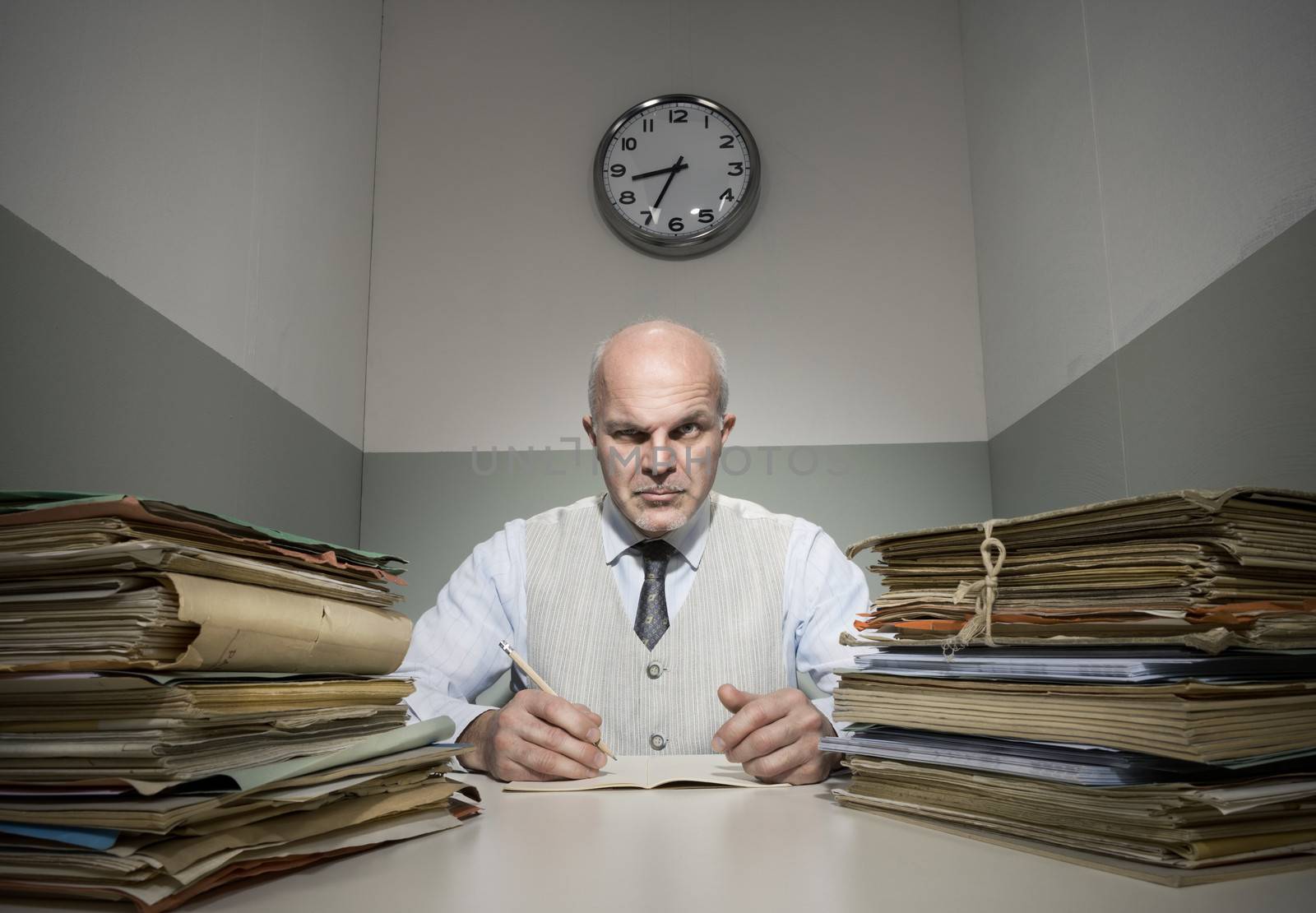 Angry office worker with piles of folders in a small room.