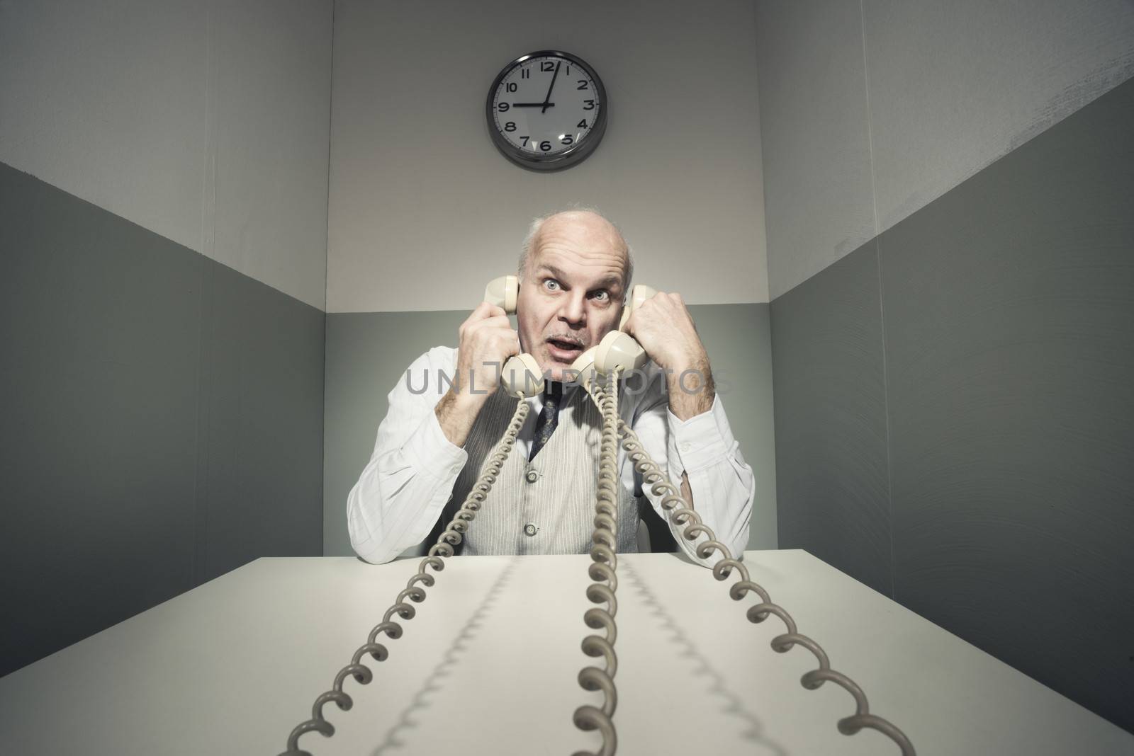 Stressed overworked businessman talking on the phone, vintage setting.