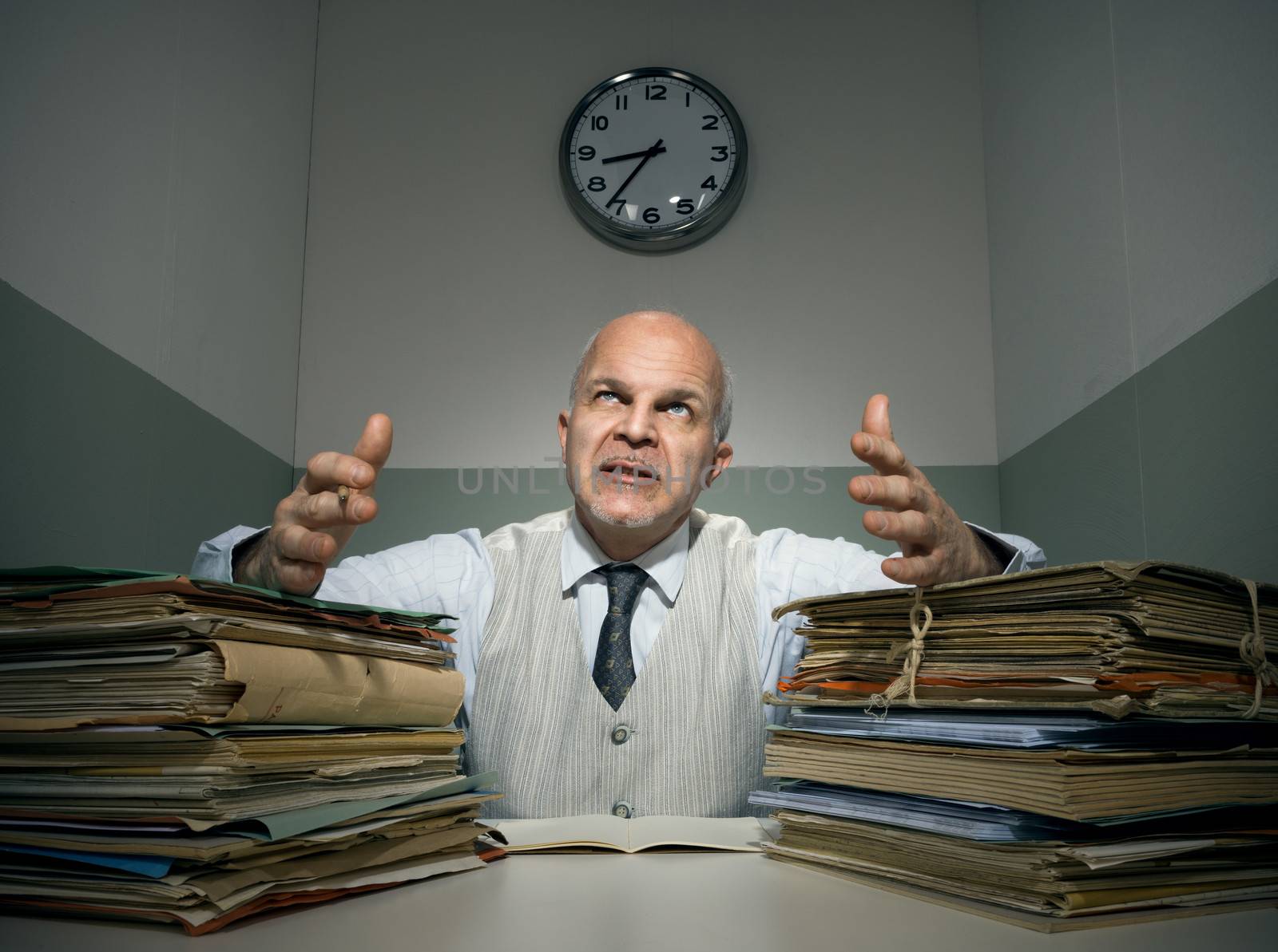 Angry office worker with piles of folders in a small room.