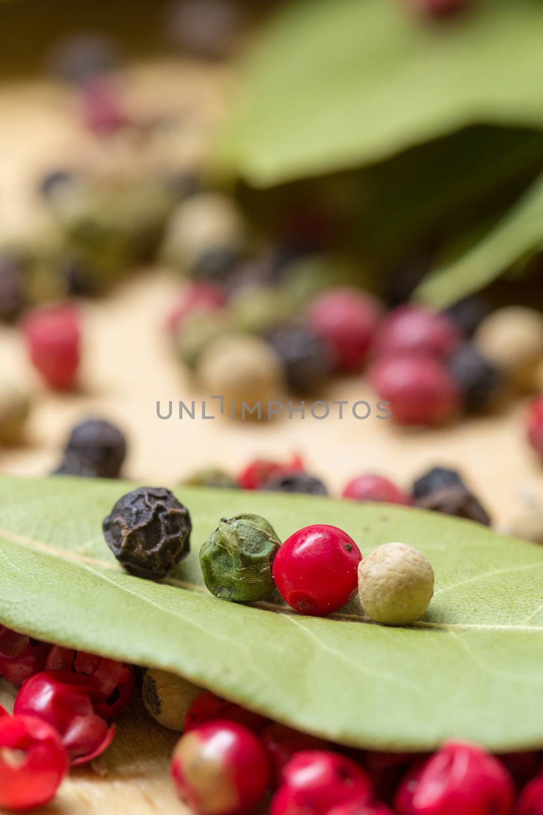 Dry bay laurel leaf with multicolored peppercorn closeup on wooden background