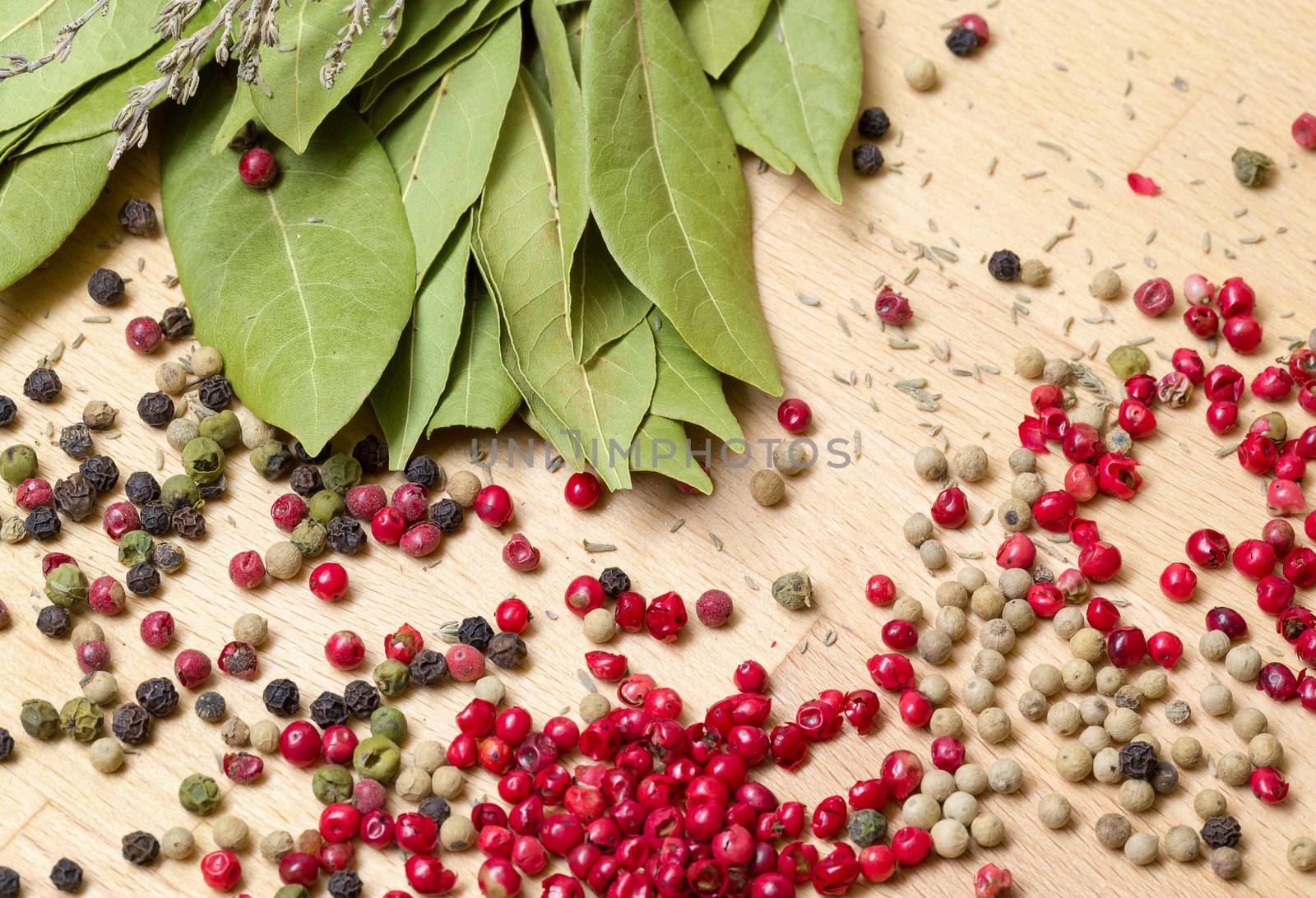 Dry bay laurel leaf with multicolored peppercorn closeup on wooden background