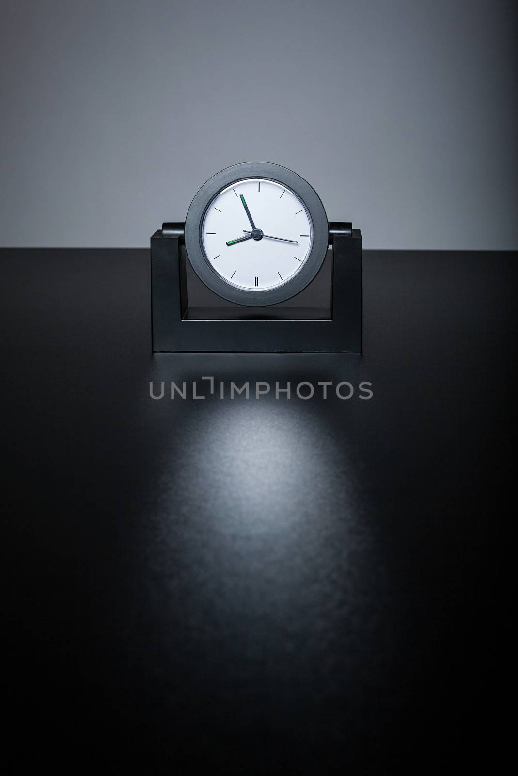 Modern black clock on black table in the office by uros93
