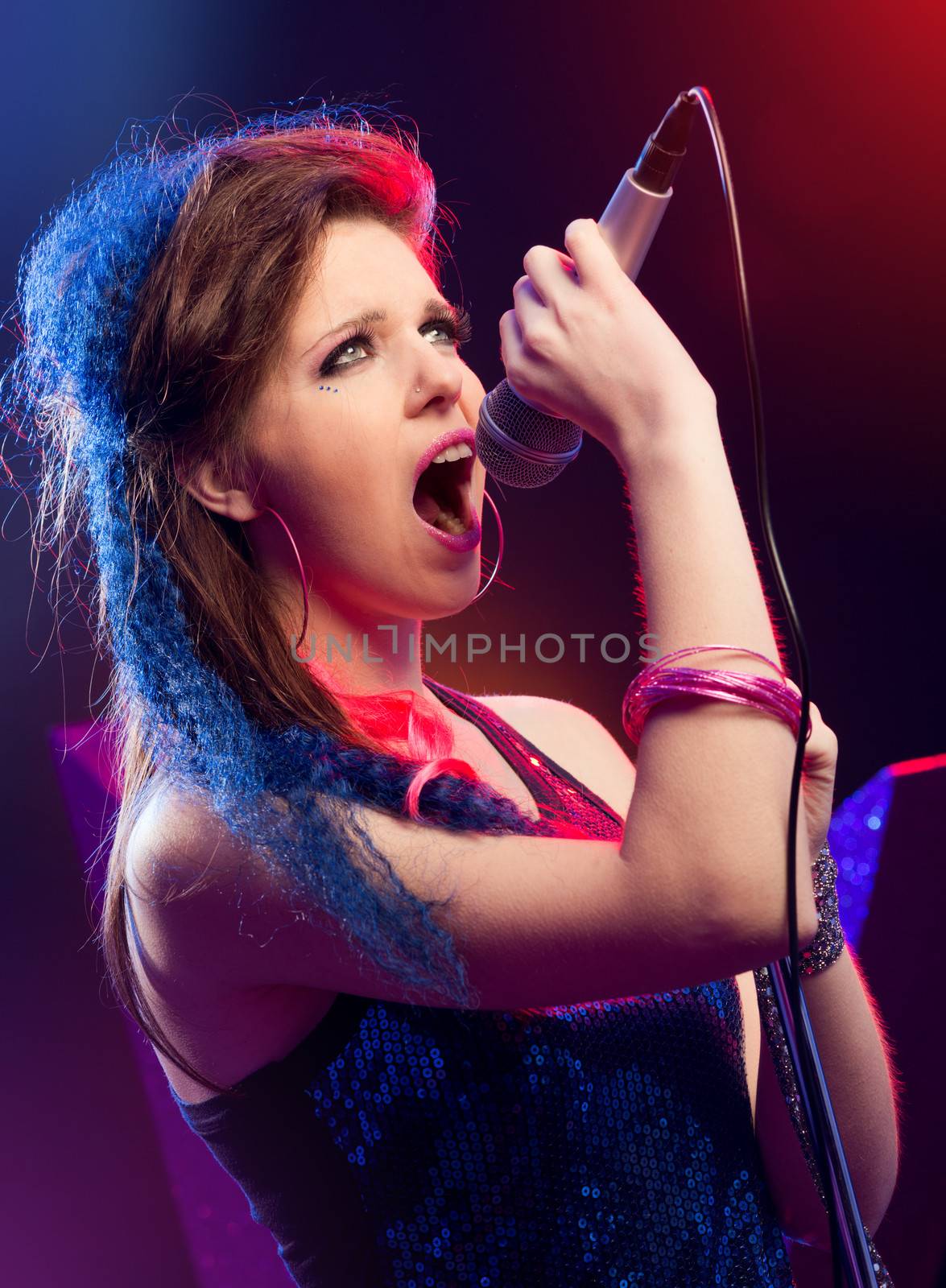 Young pop star girl singing on stage close up.