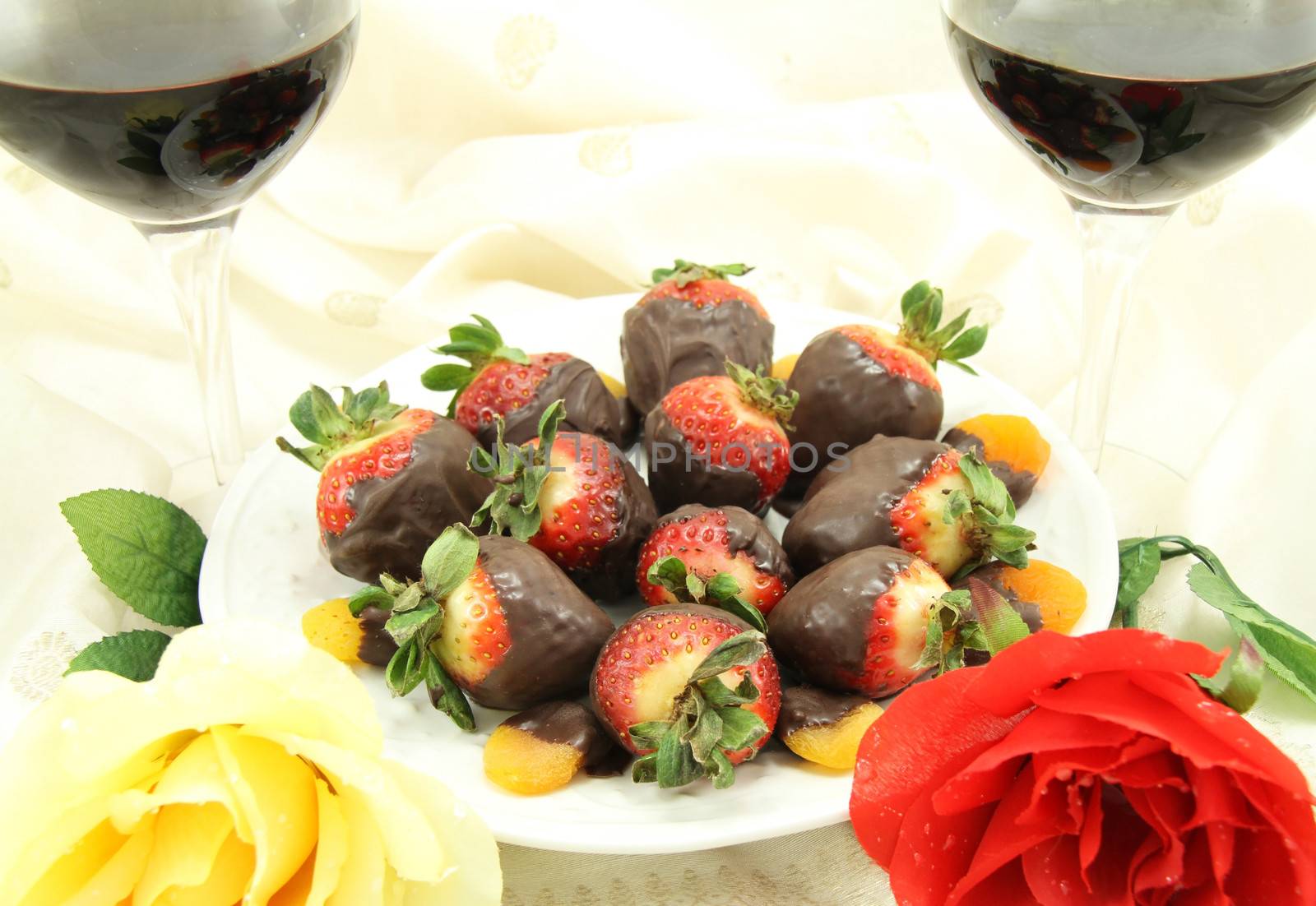 Red and white wine with chocolate covered strawberries, chocolate covered apricots and roses.