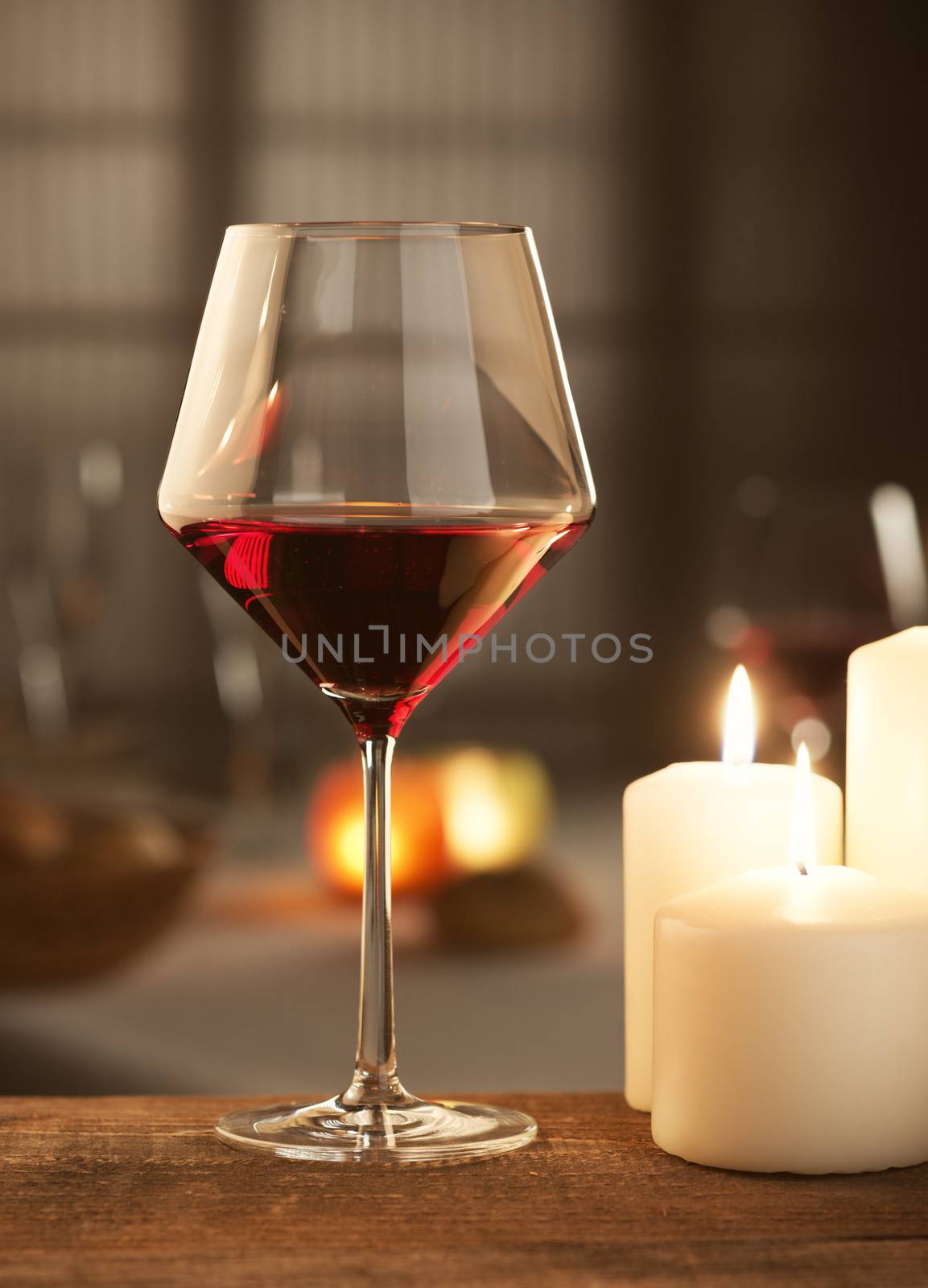 Red wine glass with candlelight and restaurant on background.
