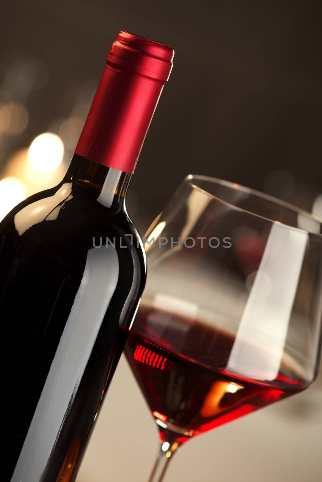 Red wine glass and bottle close up with restaurant on background.