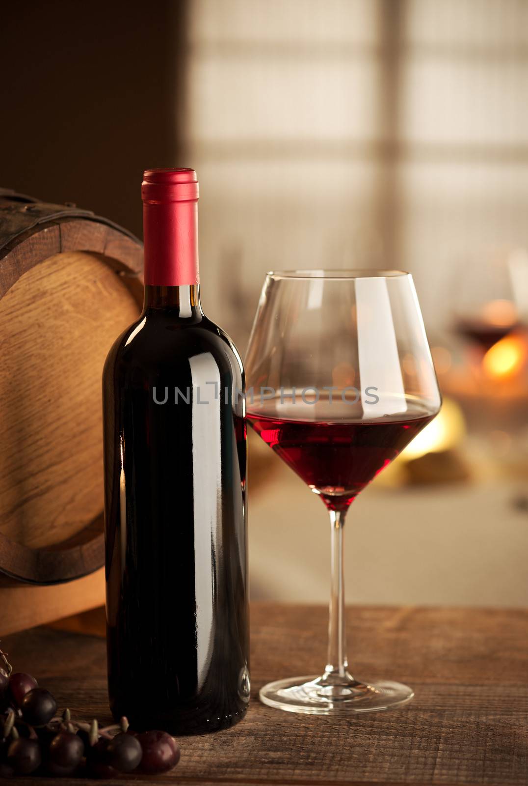 Bottle, glass, grape and barrel still life with restaurant on background.