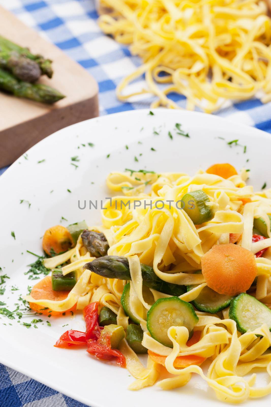 Traditional tagliatelle with summer vegetables on checkered tablecloth.