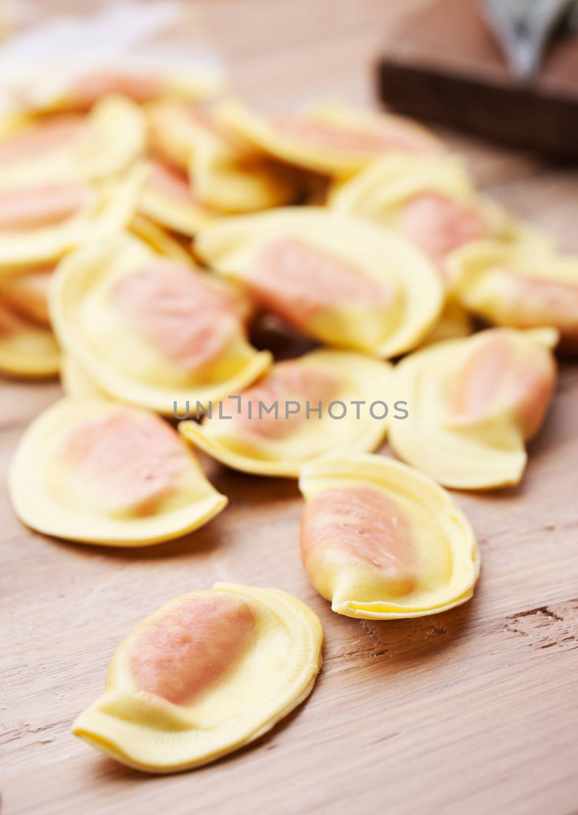 Handmade ravioli with red filling on wooden table.