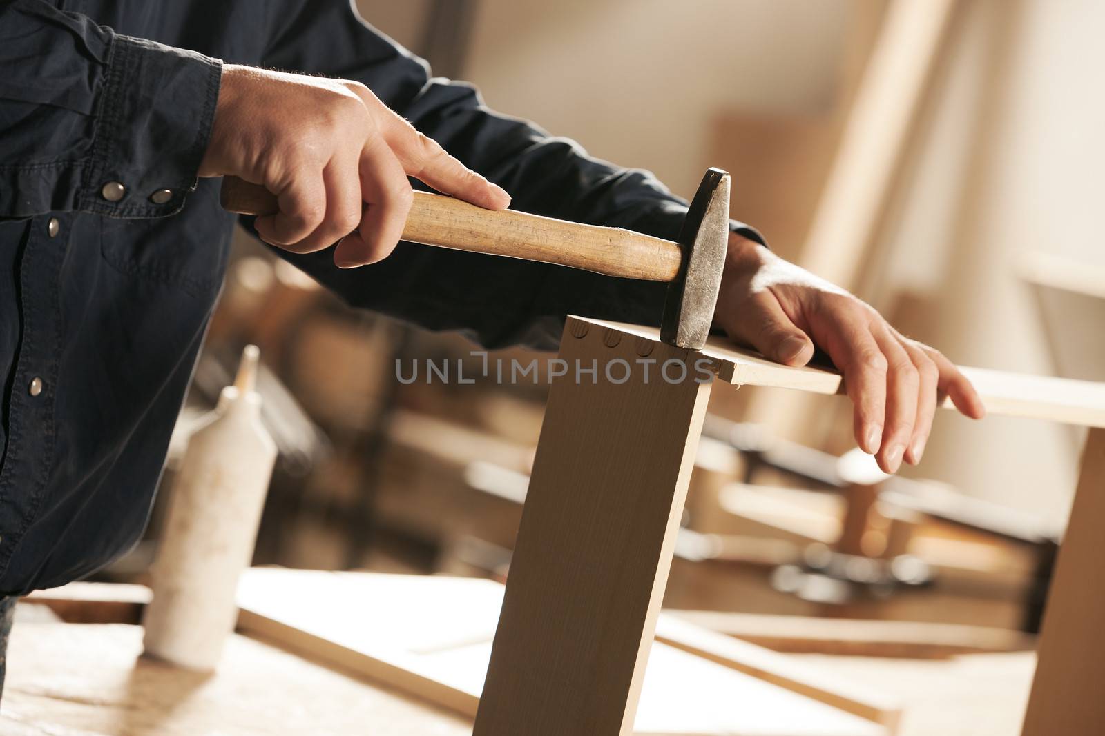 Carpenter hammering a piece of furniture for assembly.
