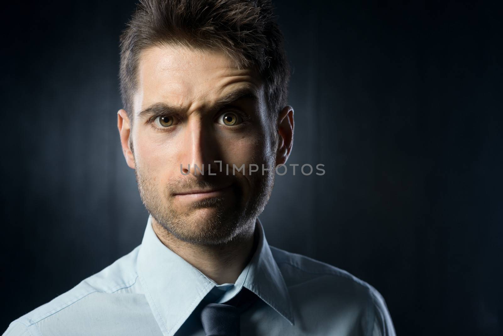 Young businessman: confused expression with raised eyebrow.