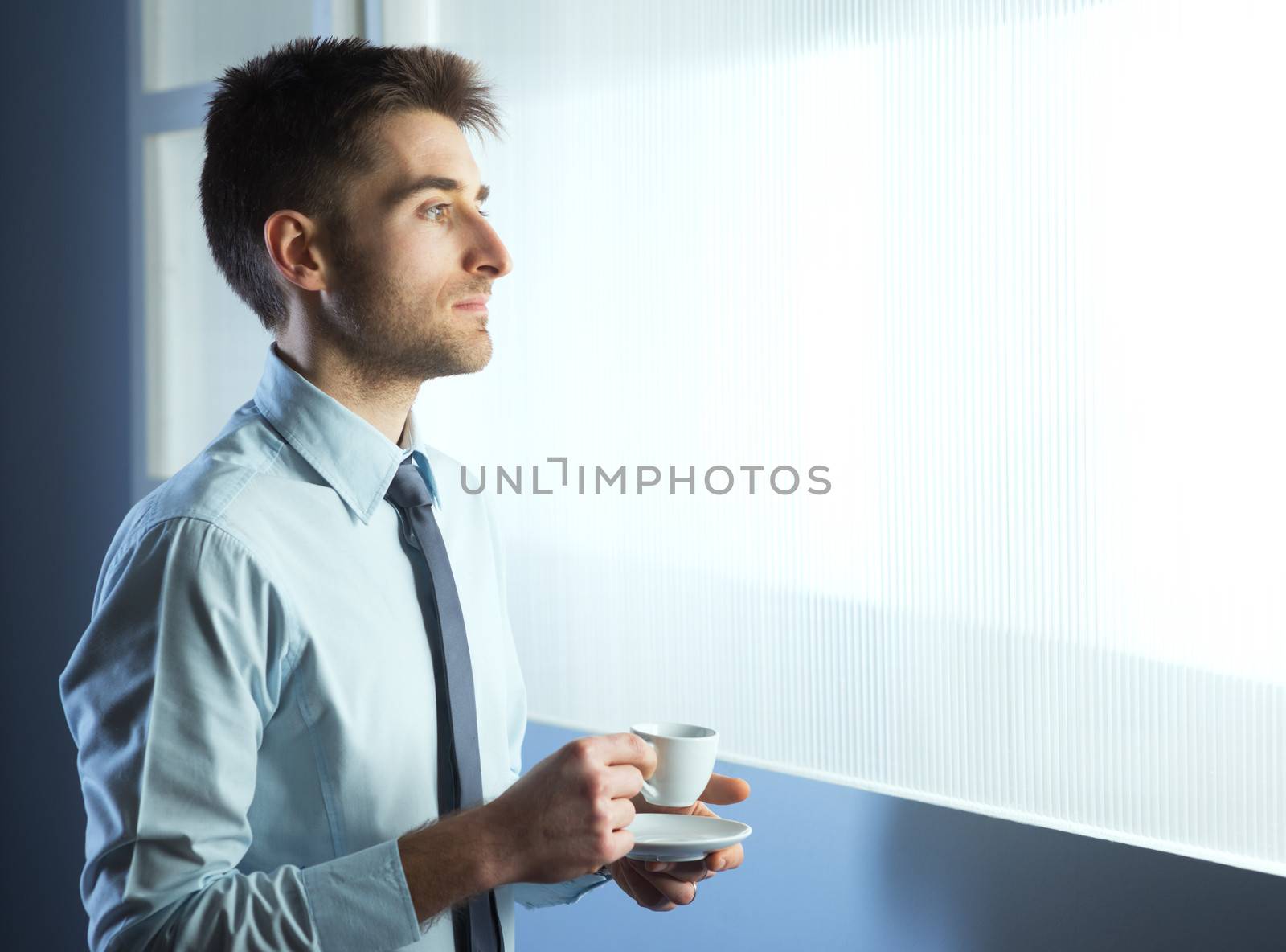 Businessman having a coffee break and relaxing at window.