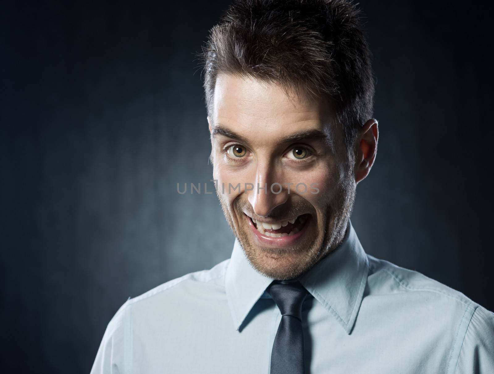 Young happy business man with funny expression on dark background.