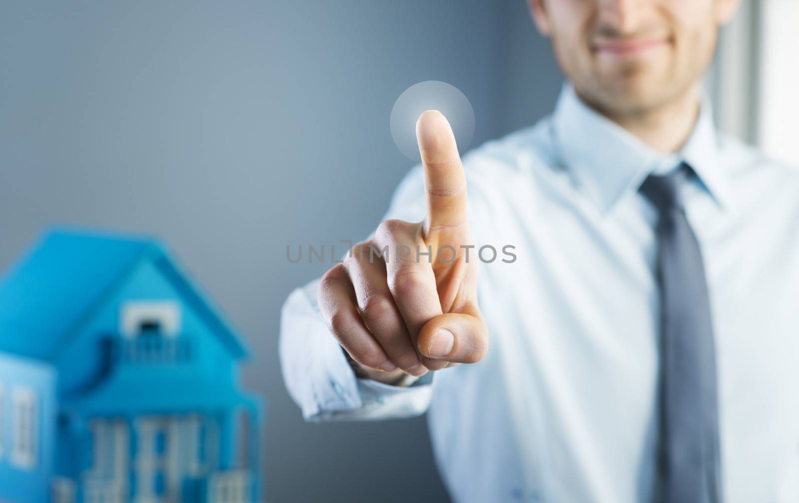 Man using touch screen interface with model house on background.