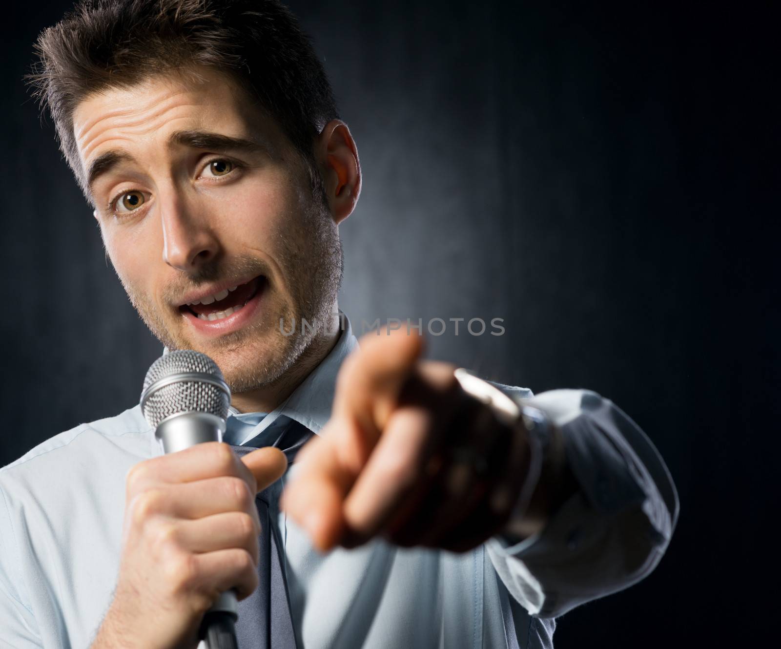 Man giving a speech with microphone and gesturing.