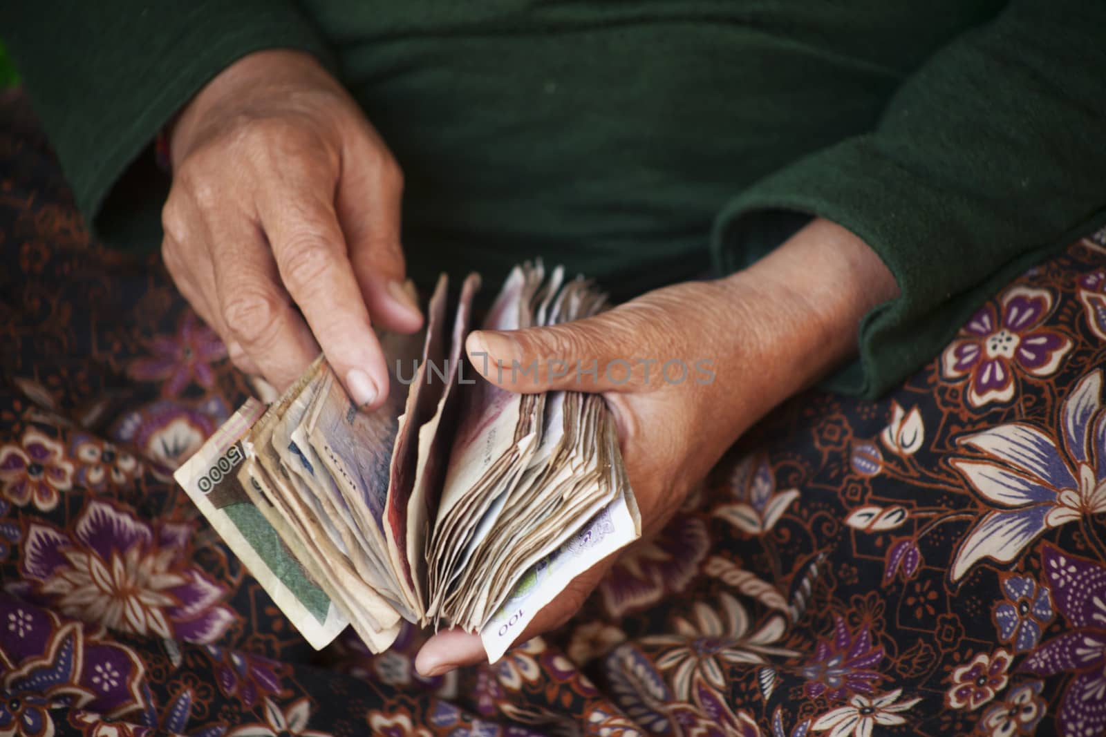 Ederly woman  counting riel notes in a market in Cambodia