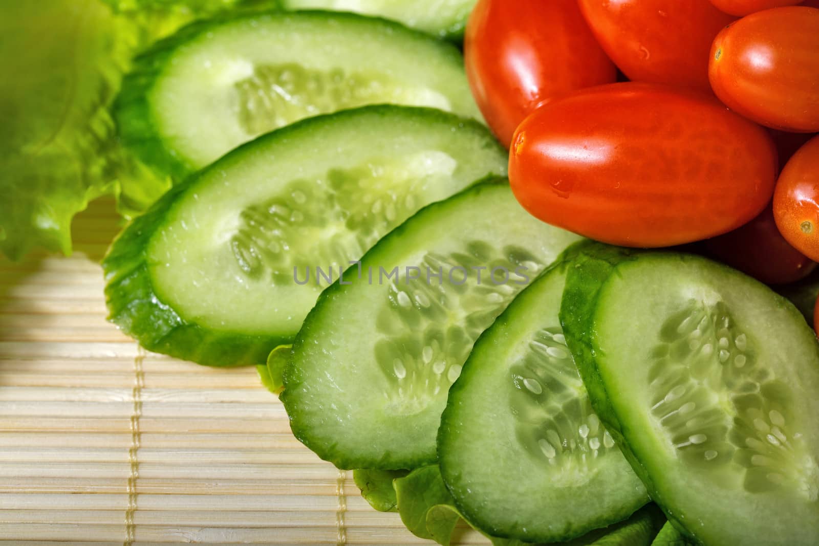 Ripe cherry tomatoes, cucumbers and lettuce closeup shot