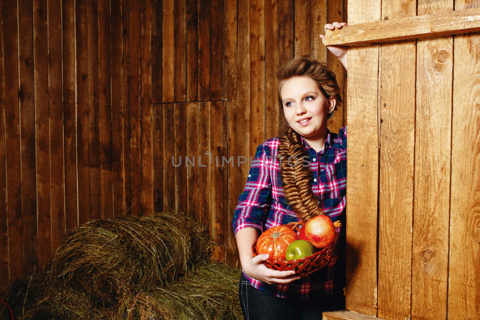 Teen girl with a plait in a barn on the farm after harvest