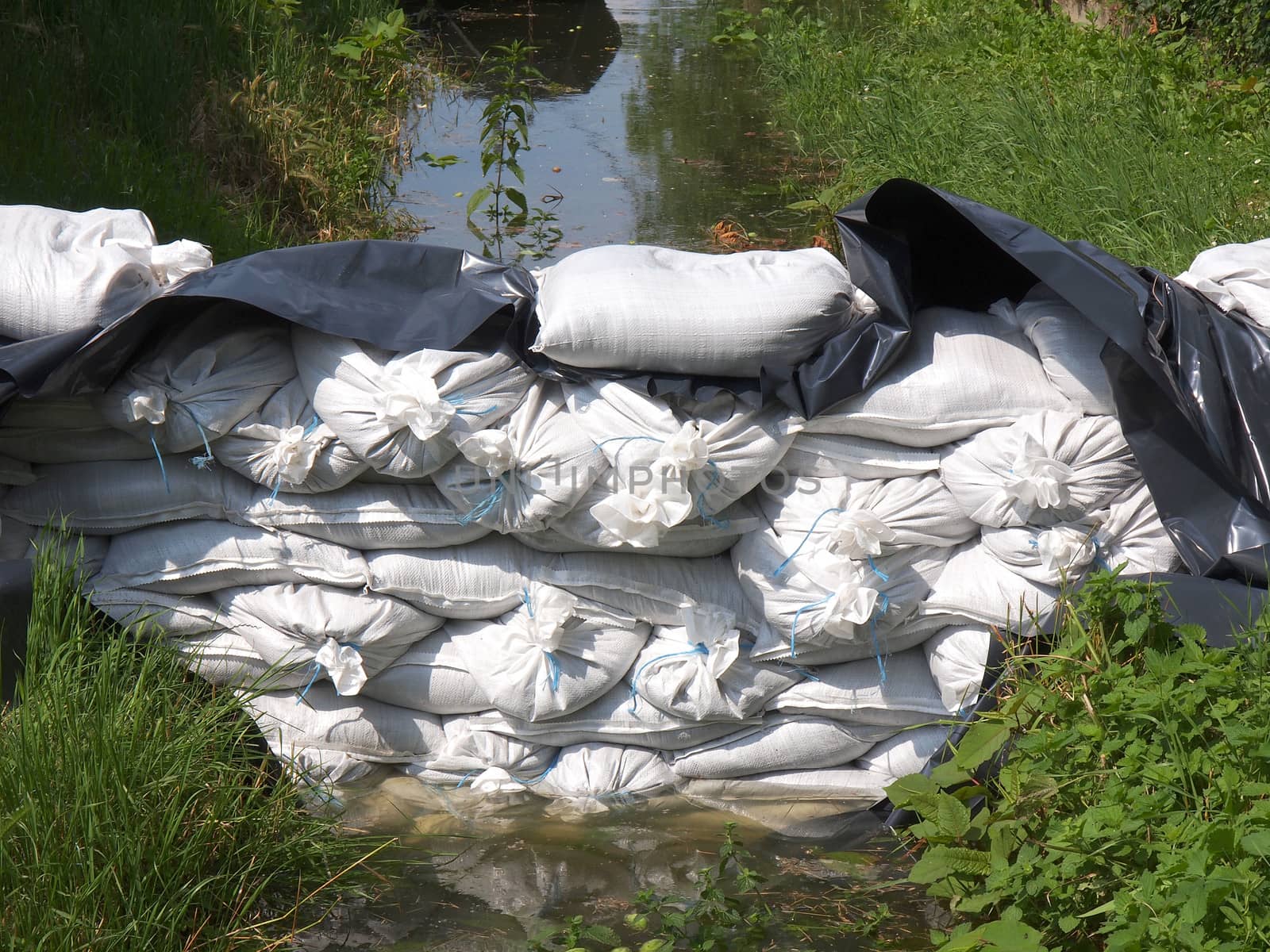 White sandbags for flood defense and brown water        