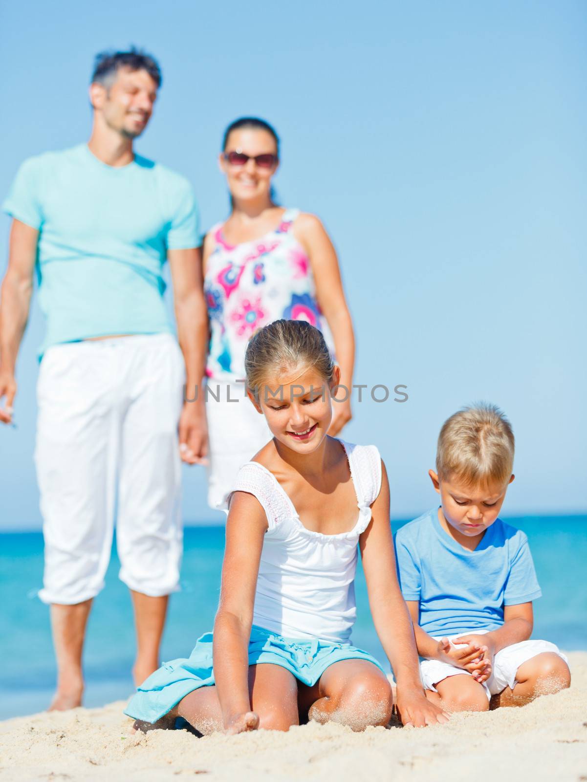 Family of four having fun on tropical beach