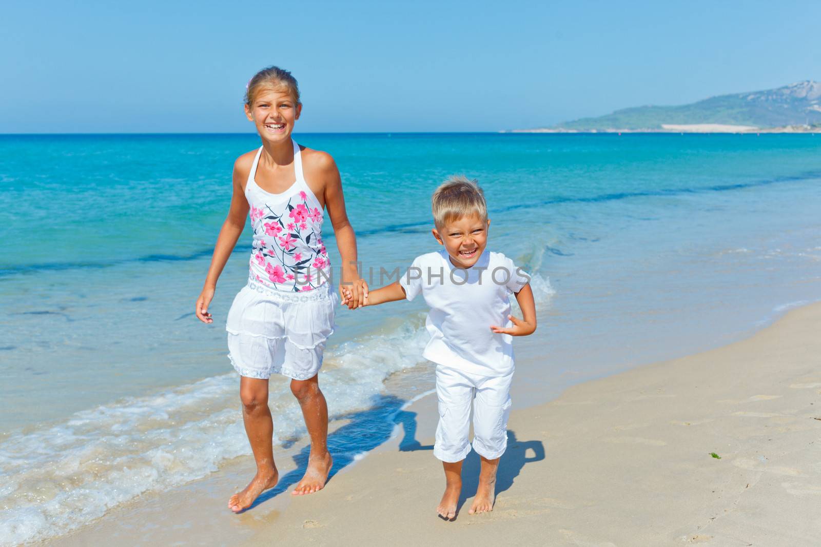 Adorable happy boy and girl runs along beach vacation