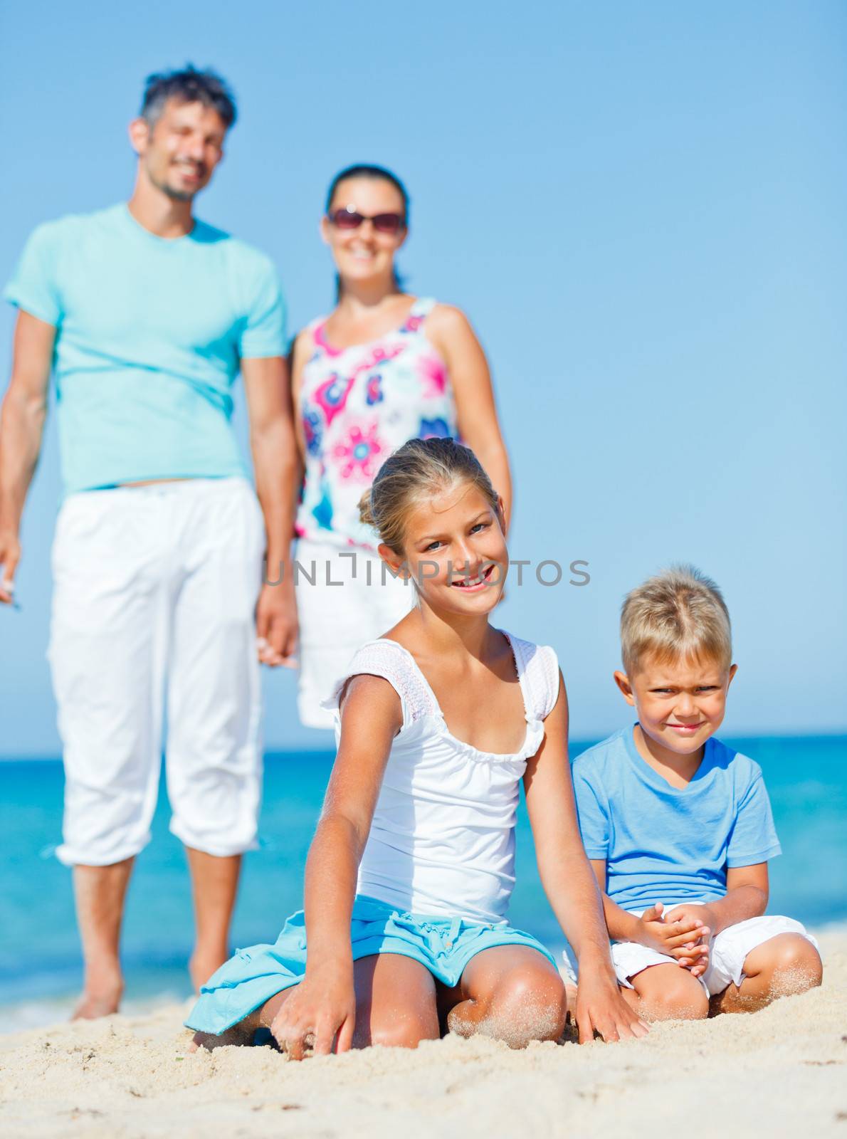 Family of four having fun on tropical beach