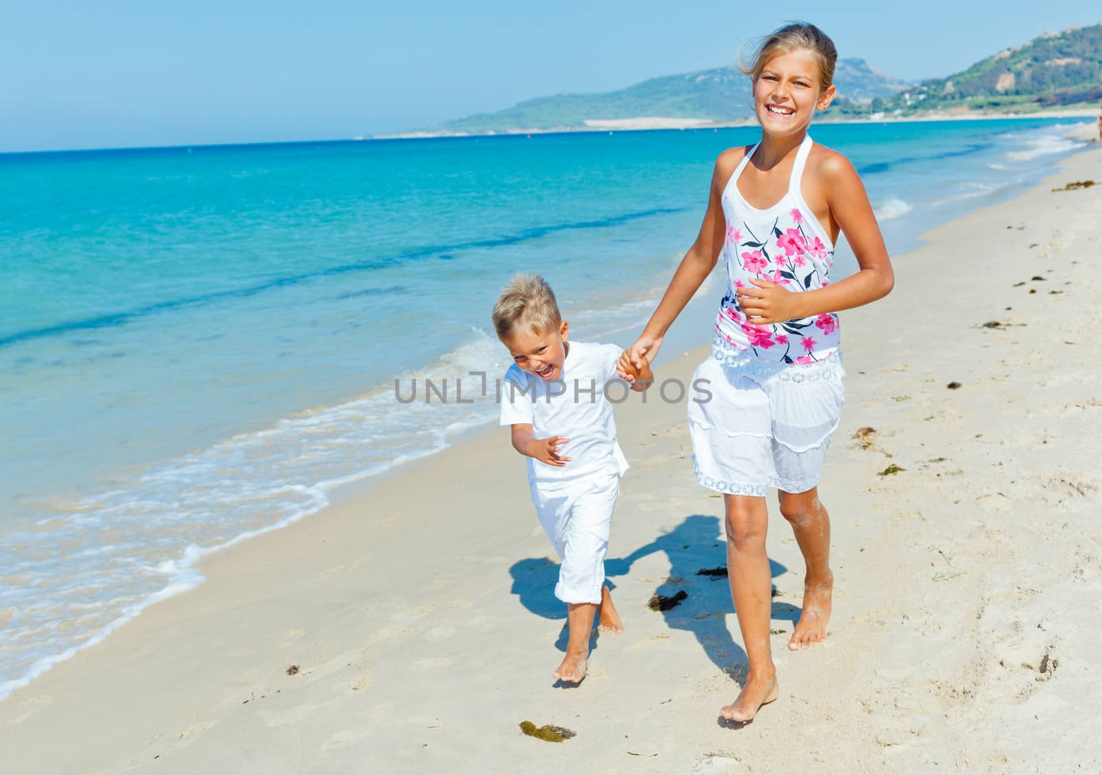 Adorable happy boy and girl running on beach vacation