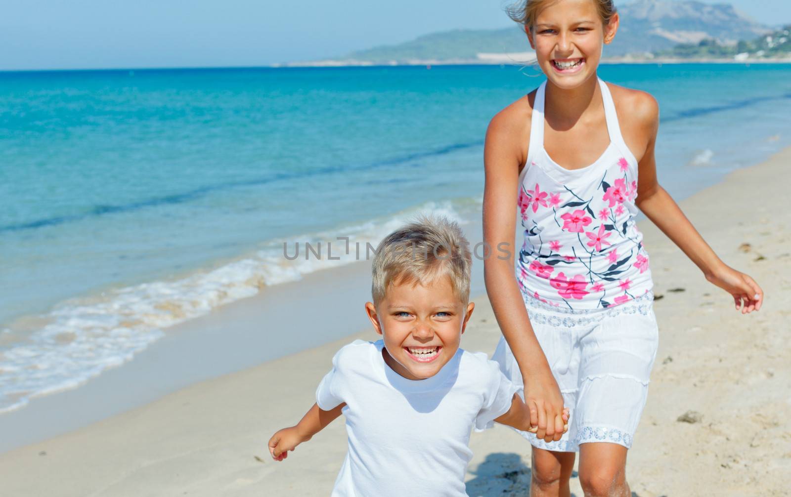 Adorable happy boy and girl runs along beach vacation