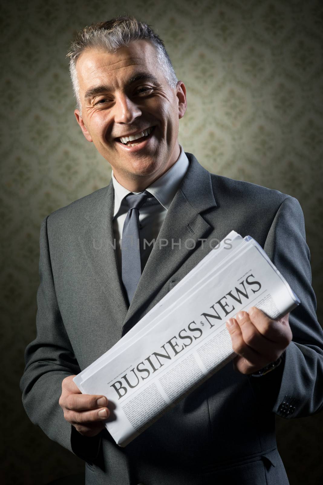 Handsome businessman holding newspaper against vintage wallpaper background.