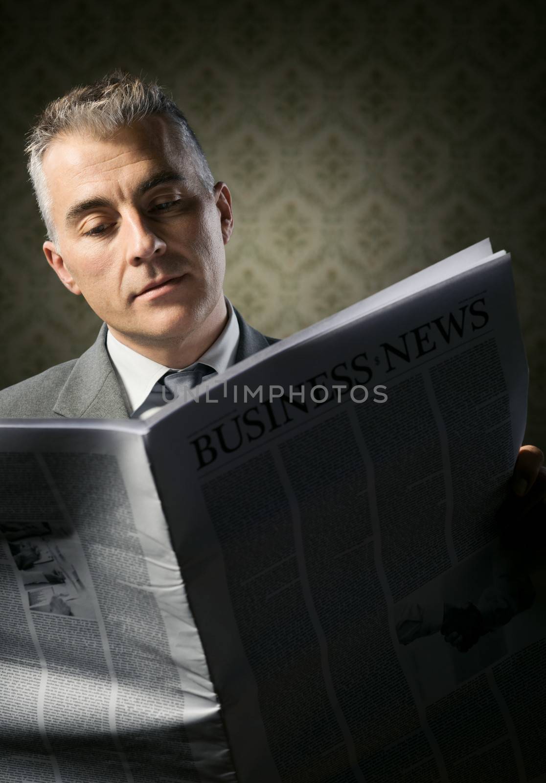 Handsome businessman reading news against vintage wallpaper background.