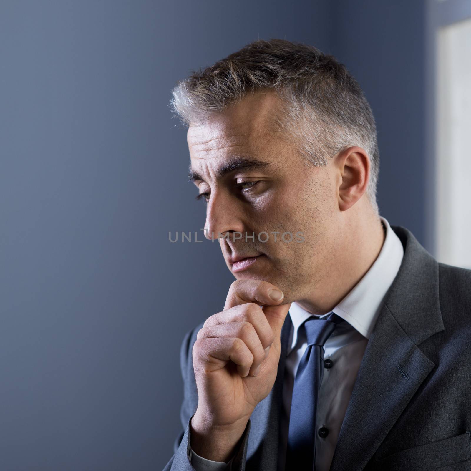 Pensive businessman with hand on chin at office.
