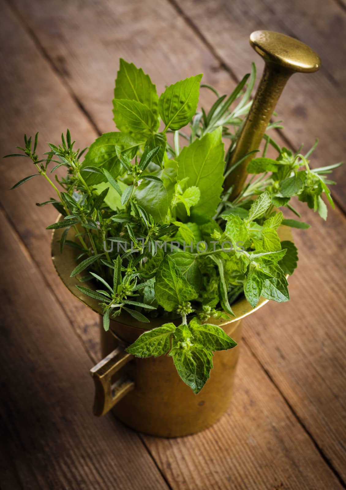 Fresh herbs in the copper mortar on the table