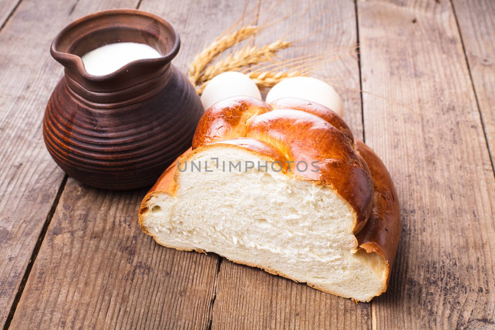 Fresh loaf of challah with milk and eggs on the table