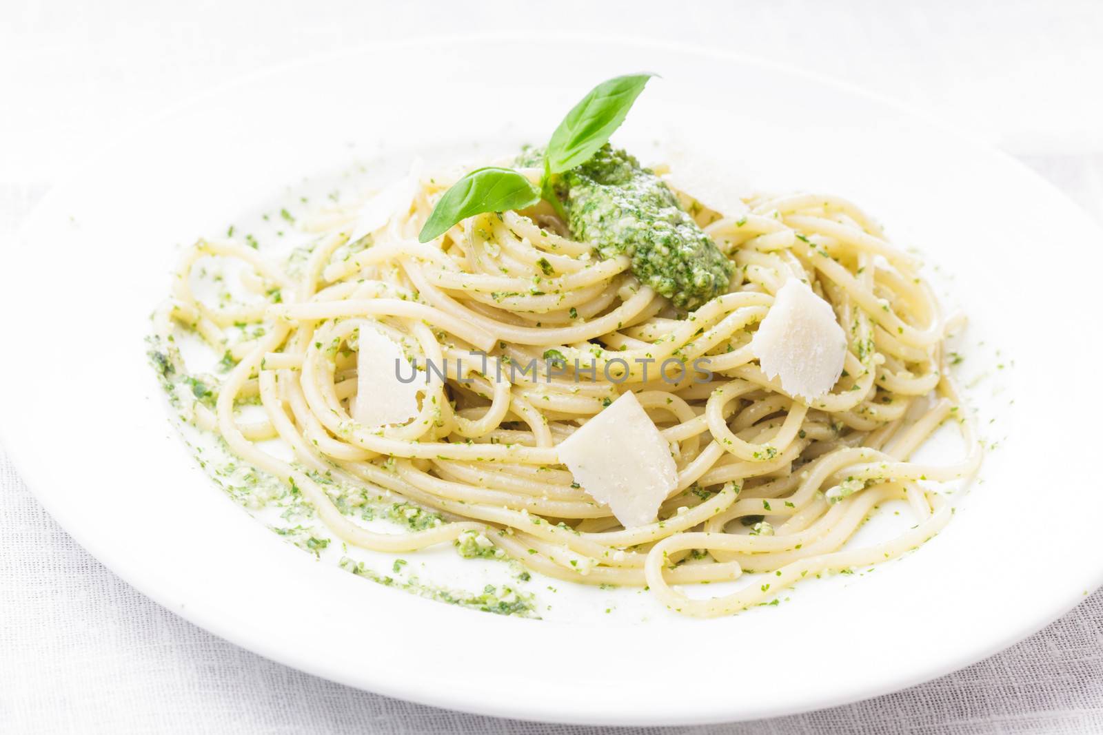 Spaghetti with green pesto and parmesan on the plate