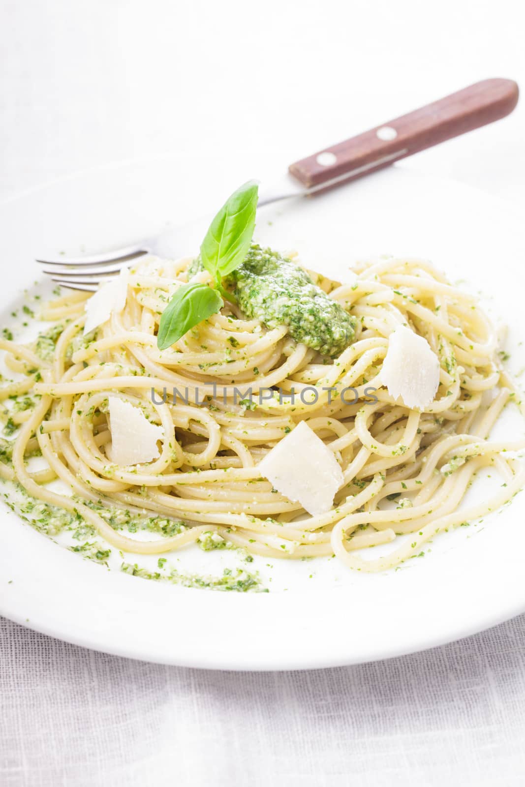 Spaghetti with green pesto and parmesan on the plate