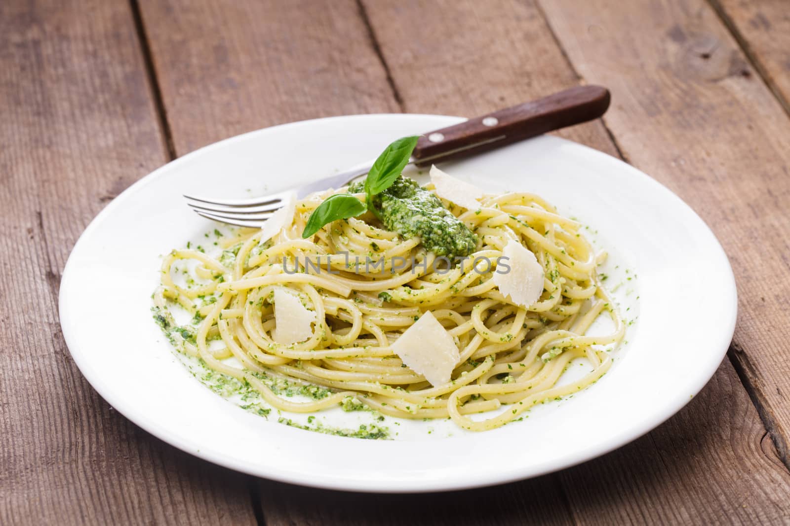 Spaghetti with green pesto and parmesan on the plate