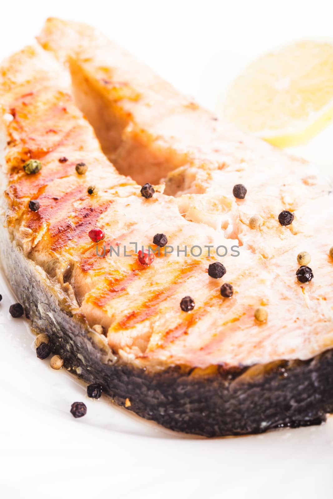 Salmon grilled steak with peppercorn and lemon close up