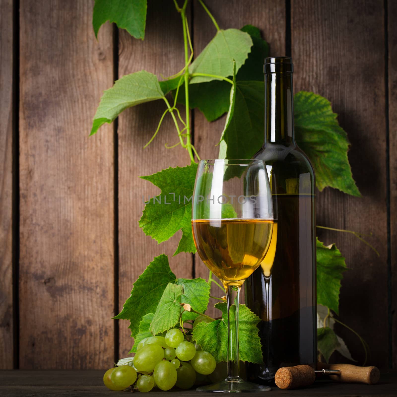 White wine, grapes, corkscrew, and bottle on wood background closeup