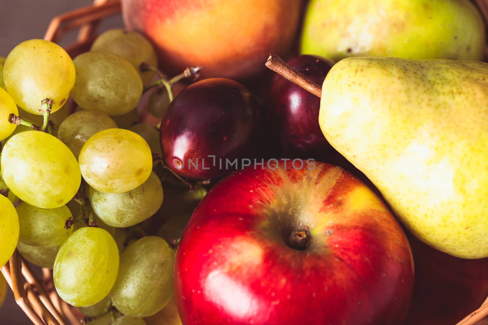 Autumnal fruits in the basket as a background