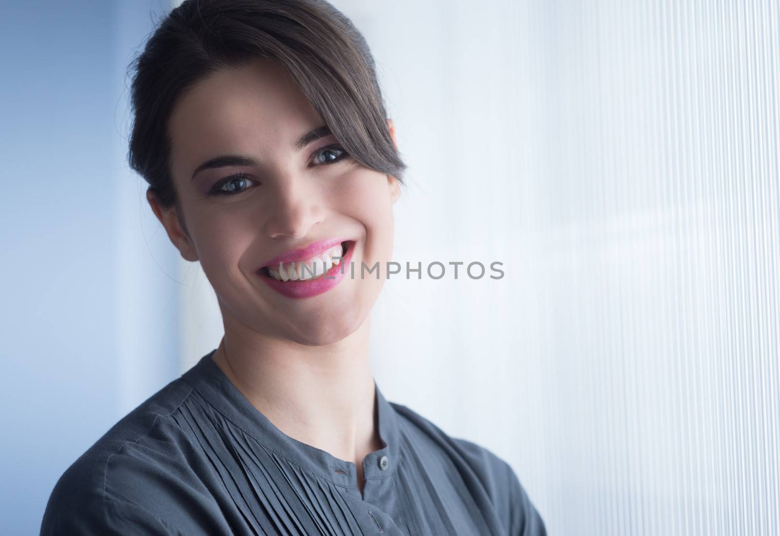 Young attractive woman smiling next to the window and looking at camera.