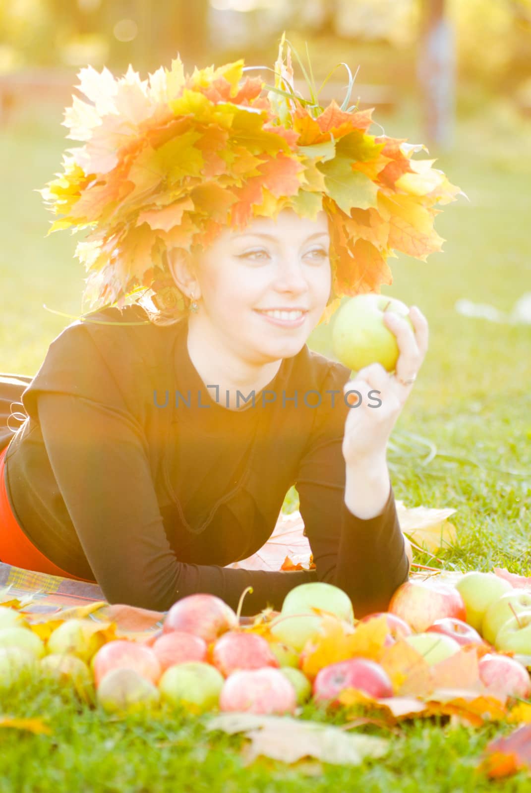 Woman in garland of maple leafs and apple crop. Autumn decorations