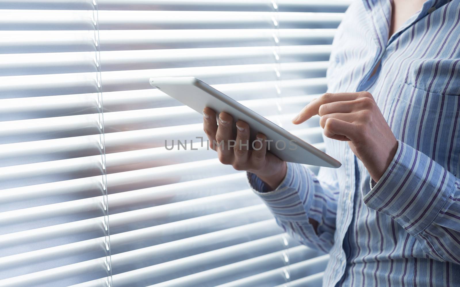 Young woman using a digital tablet in front of a window.