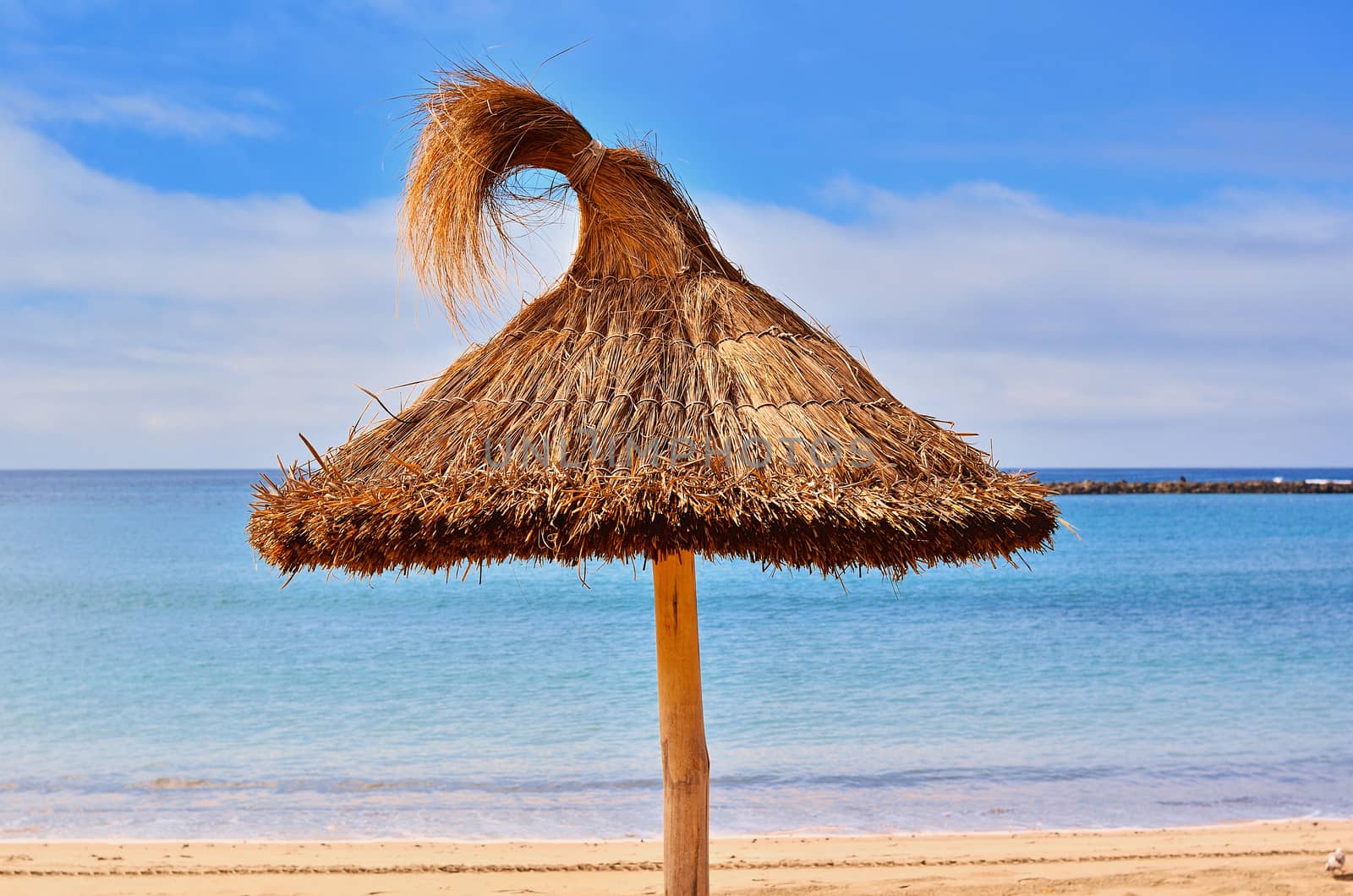 Straw sunshade on the sandy seashore