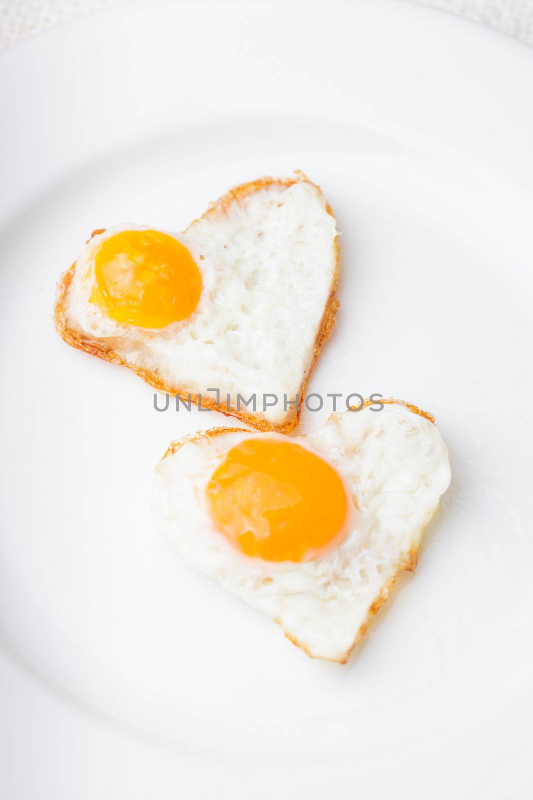 Heart shape fried eggs on the white plate