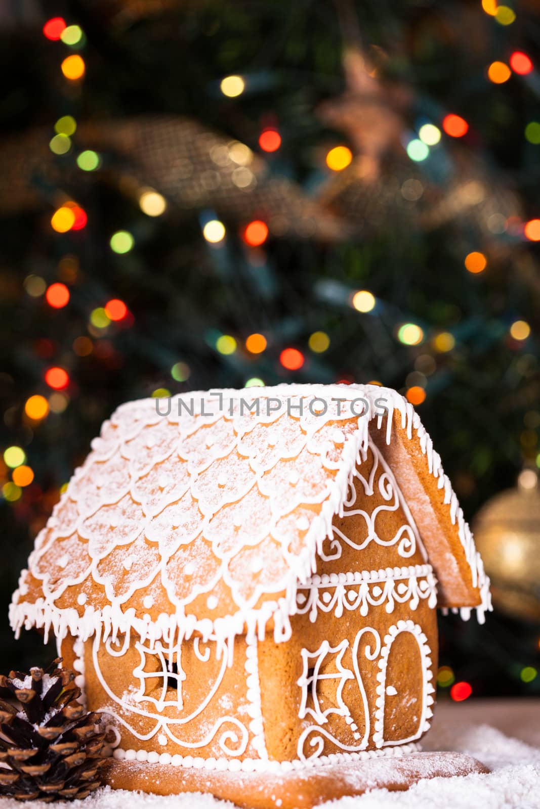 gingerbread house over defocused lights of Chrismtas decorated fir tree